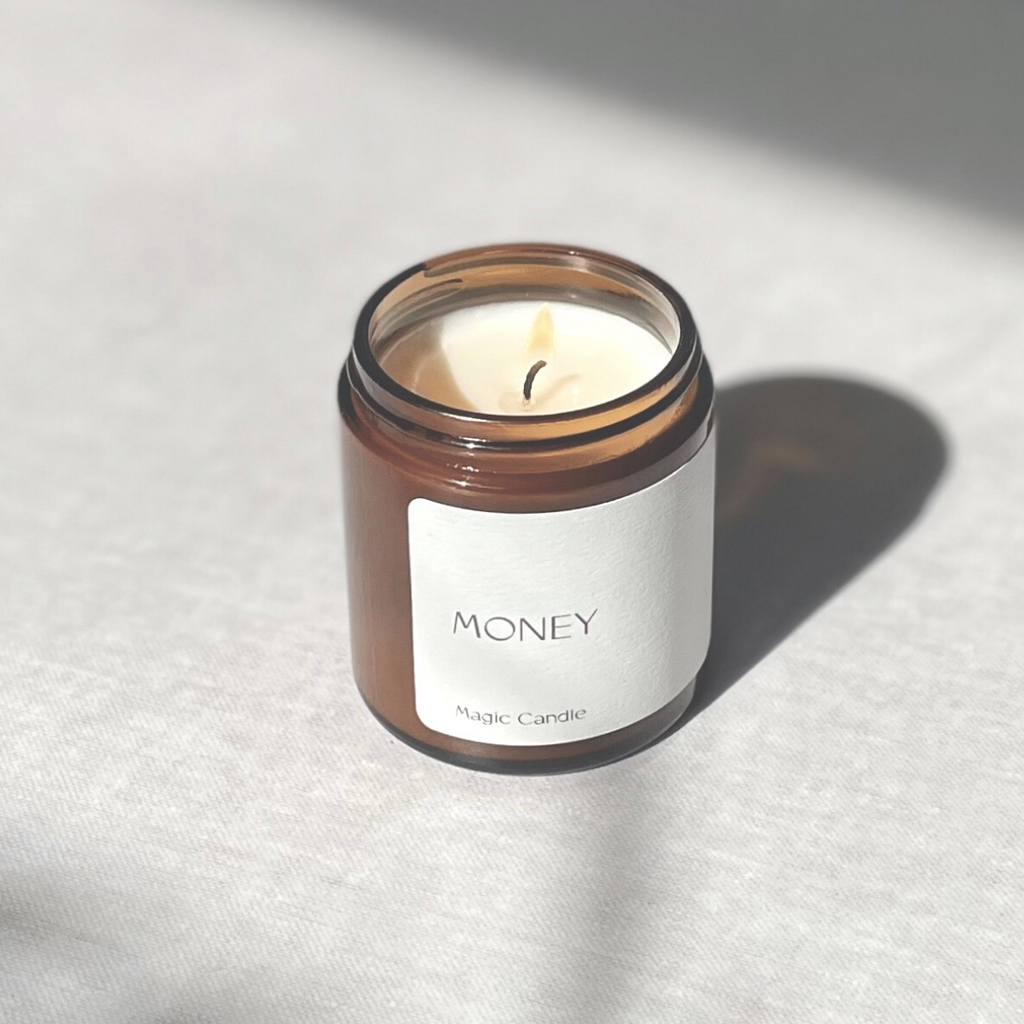 Species by the Thousands Money Magic Candle in an amber jar with a minimal white paper label.