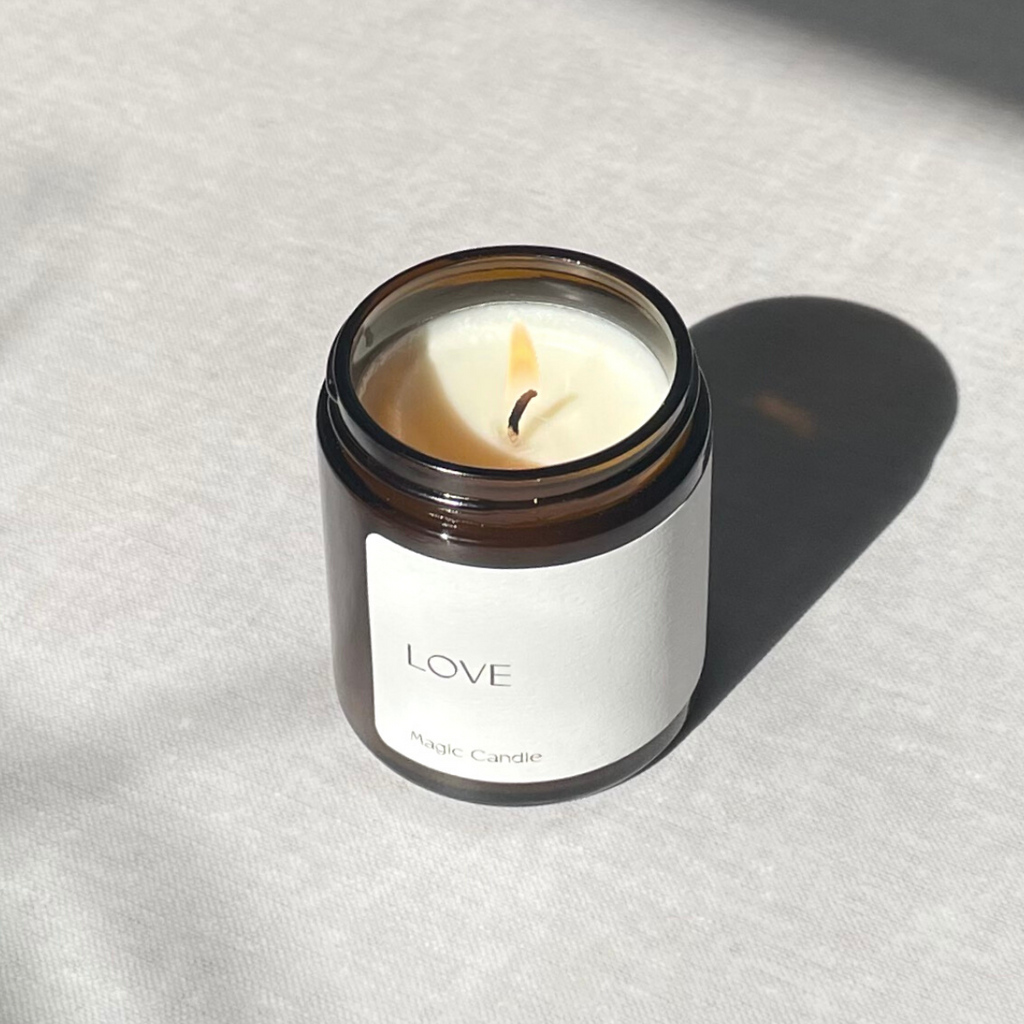 Species by the Thousands Love Magic Candle in an amber jar with a minimal white paper label.