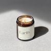 Species by the Thousands Earth Elemental Magic Candle in an amber jar with a minimal beige paper label.